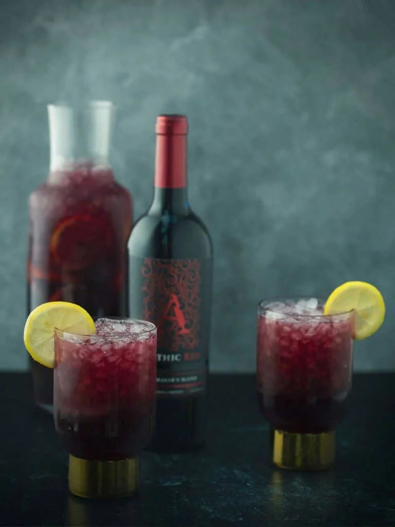 Two glasses and a pitcher of Apothic Irish sangria and a bottle of Apothic red