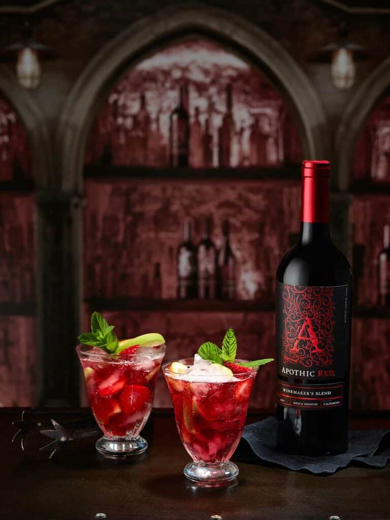 Two glasses of rebellious red sangria cocktail and a bottle of Apothic Red
