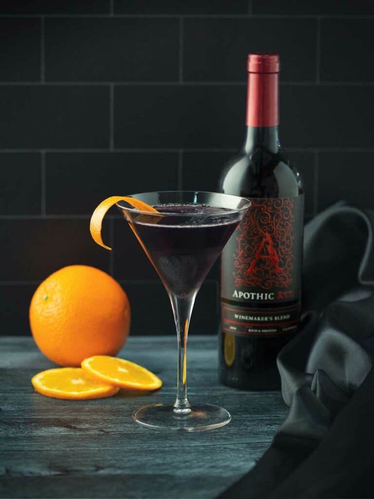 A glass of Apothic red cosmo with an orange and a bottle of Apothic Red