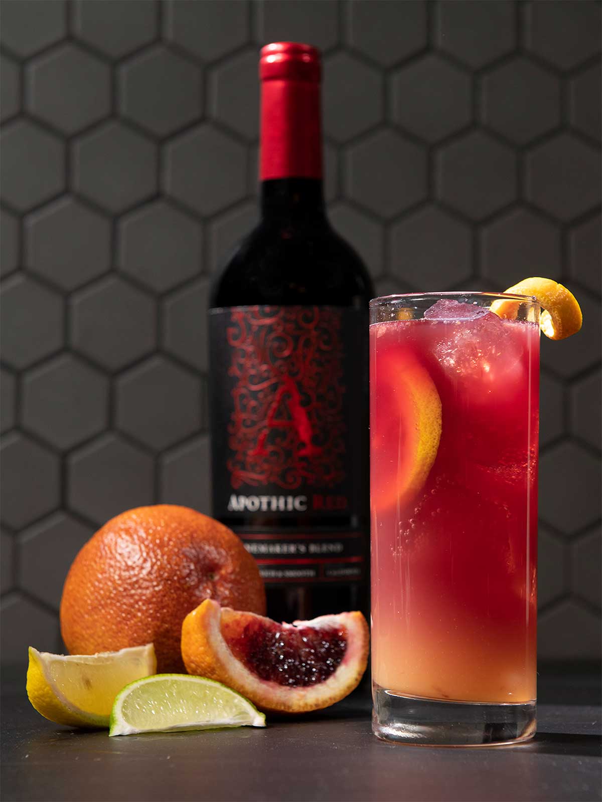 A glass of Apothic sunrise cocktail with citrus and a bottle of Apothic Red