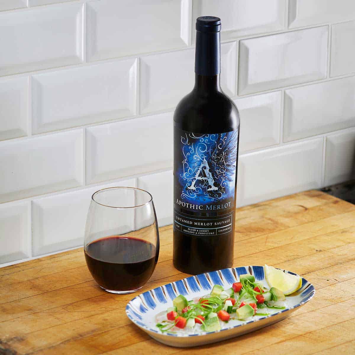 A crudities plate in front of a glass and a bottle of Apothic merlot
