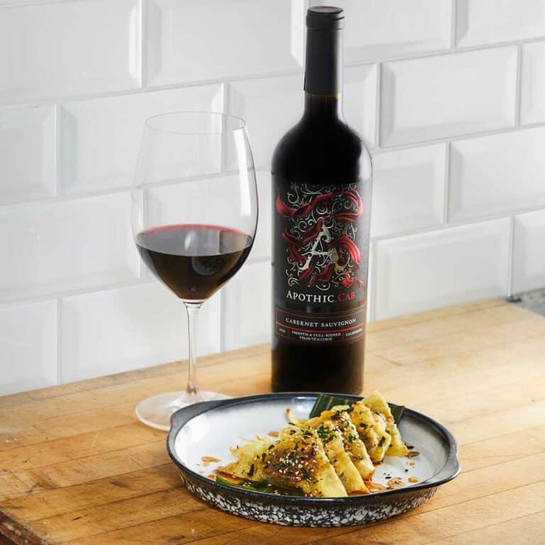 Oxtail dumplings in a plate in front of a glass and a bottle of Apothic Cab